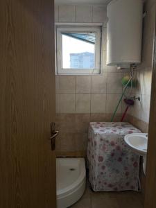 a bathroom with a toilet and a sink and a window at Ring Urban Apartment in Kosovo Polje +12 photos