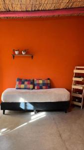 a bed in a room with an orange wall at Tale Cabaña de campo in Huacalera +3 photos