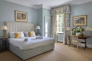 a bedroom with a large bed and a desk and a window at Abbey House by Group Retreats in Saffron Walden +72 photos