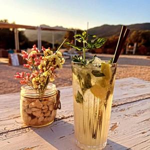 two drinks sitting on a wooden table with flowers at Pasare Glamping_AnglonaRuralExperience in Perfugas
