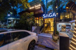 a white car parked in front of a saaq store at The Saga Hotel Green Park in New Delhi