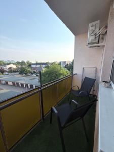 a balcony with two chairs and a view of a building at Sarah Doe Apartman in Nyíregyháza