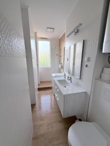 a white bathroom with a sink and a toilet at Sarah Doe Apartman in Nyíregyháza +10 photos