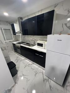 a white kitchen with black cabinets and a white refrigerator at Gandía Jacuzzi Suites in Gandía