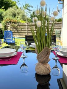 a table with wine glasses and a vase with flowers at Résidence de la Presqu'île in Plougonvelin