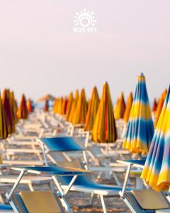 a row of chairs with umbrellas on a beach at HOTEL BLUE SKY in Rimini