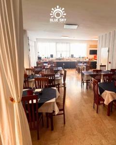 a dining room with tables and chairs and a restaurant at HOTEL BLUE SKY in Rimini