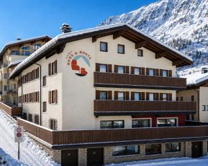 a building with a snow covered mountain in the background at Alpina`s Beds & Boots in Obertauern