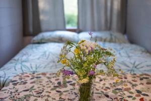 a vase of flowers on a table with a bed at Glamping Walden in Nový Hrozenkov