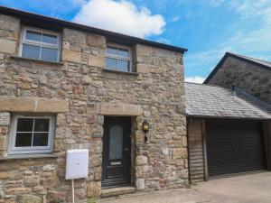 a stone house with a black door and a garage at Gews Farm Lodge in Penzance