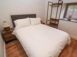 a bedroom with a white bed and a window at Gews Farm Lodge in Penzance