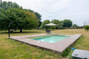 ein Schwimmbecken mit einem Tisch und einem Sonnenschirm in der Unterkunft O Lagar de Jesus in Padrón
