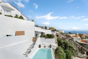 a white house with a swimming pool on a hill at Cueva Sol in Fasnia