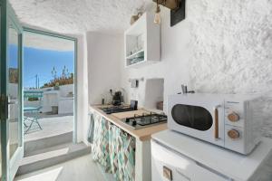 a white kitchen with a microwave and a stove at Cueva Sol in Fasnia