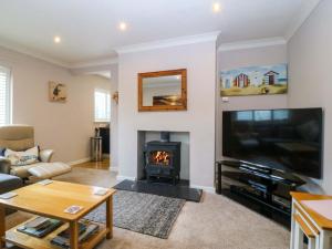 a living room with a fireplace and a flat screen tv at 5 Ger Afon in Pwllheli