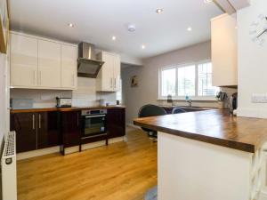 a kitchen with white cabinets and a wooden counter top at 5 Ger Afon in Pwllheli