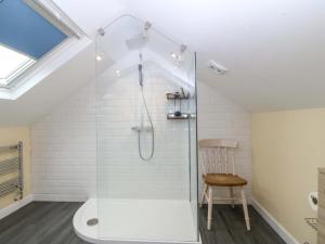 a bathroom with a glass shower with a chair at 5 Ger Afon in Pwllheli +27 photos