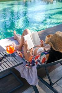 a woman laying on a towel reading a book next to a pool at Hotel Alicante Golf in Alicante