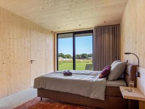 a bedroom with a large bed and a large window at Villa WOOD in Elsendorp
