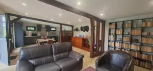 a living room with a leather couch and book shelves at Le Rameau Gîte avec spa et étangs privés in Langey
