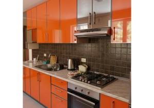 a kitchen with orange cabinets and a stove top oven at Forest Edge Guesthouse in Aghavnadzor