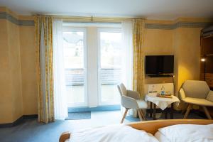 a bedroom with a bed and a table and a tv at Hotel Bischof in Schmallenberg