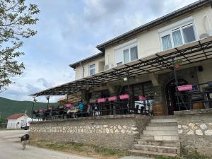 a dog standing outside of a building with a restaurant at Hotel Riva in Stenje