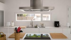 a white kitchen with a sink and a microwave at Villa Guvalmar Chalet Roche in Roche