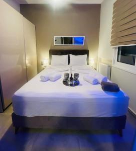 a bedroom with a large white bed with two glasses on it at Phoenix Garden Apartments - 4 - in Athens