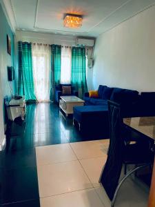 a living room with a blue couch and green curtains at Renova-Immo in Yaoundé