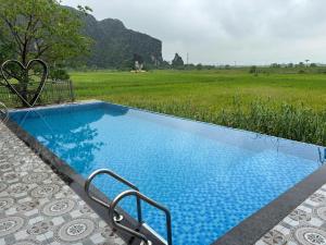 a blue swimming pool with a view of a field at L'Ananas Garden Homestay in Vũ Lâm