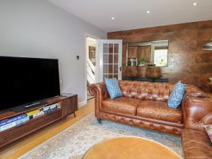 a living room with a brown leather couch and a flat screen tv at The Dacha in Winchester