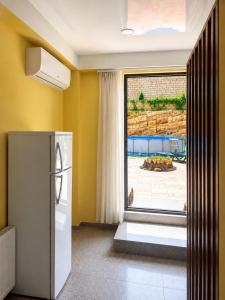 a kitchen with a refrigerator and a large window at Panorama Hills Apart-Hotel in Tbilisi City