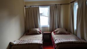 two beds in a room with a window at Patagonia Oley in Puerto Aisén