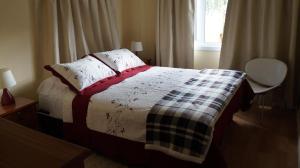 a bedroom with a bed with a blanket and a window at Patagonia Oley in Puerto Aisén