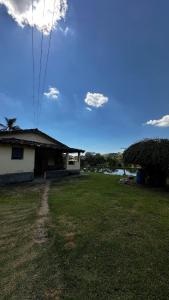 a yard with a house and a blue sky with clouds at Recanto 2 irmãos in Socorro
