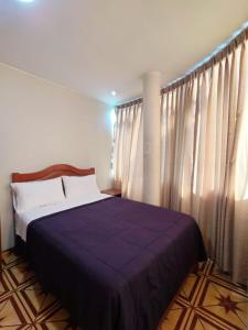 a bedroom with a bed with a purple blanket at Hallpa Ica in Ica