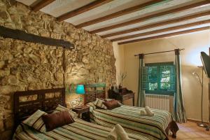 a bedroom with two beds and a stone wall at Complejo Rural La Tahona De Besnes in Alles