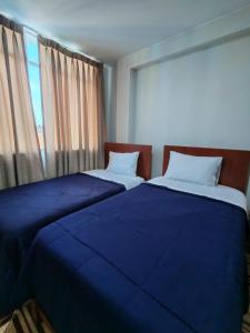 two beds with blue sheets in a room with a window at Hallpa Ica in Ica +12 photos