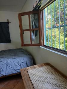 a bedroom with a window and a bed and a table at PETIT PARADIS CABAÑA Catemaco Rainforest Nature in Catemaco