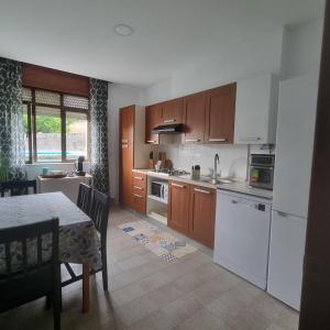 a kitchen with white appliances and a table with chairs at Dorna Vella in Valdoviño