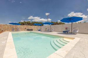 a swimming pool with chairs and blue umbrellas at Villa Cassandra in Alliste