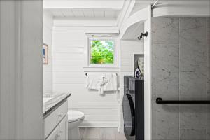 a white bathroom with a toilet and a window at Margarita Days in Seagrove Beach