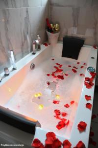 a bathroom with red rose petals on a bath tub at Lemon & Jacuzzi in Boguszów-Gorce