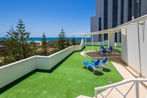 uma varanda com cadeiras e relva num edifício em The Ritz Resort Heated Pool em Gold Coast