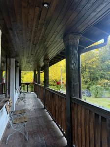 a wooden porch with chairs and a large window at Белите Къщи in Seltse