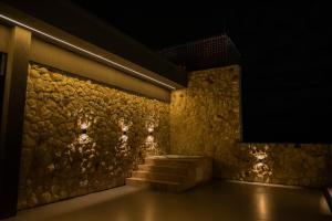 a room with a stone wall with stairs and lights at Palhoça Hotel in Canindé