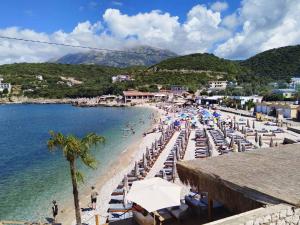 a beach with chairs and umbrellas and people on it at Vila Maša in Utjeha