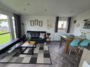 a living room with a black couch and a table at PRACHTiG CHALET ZONNESTRAAL in Westerland
