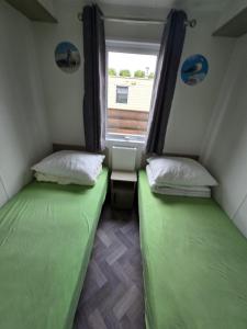 two beds in a small room with a window at PRACHTiG CHALET ZONNESTRAAL in Westerland